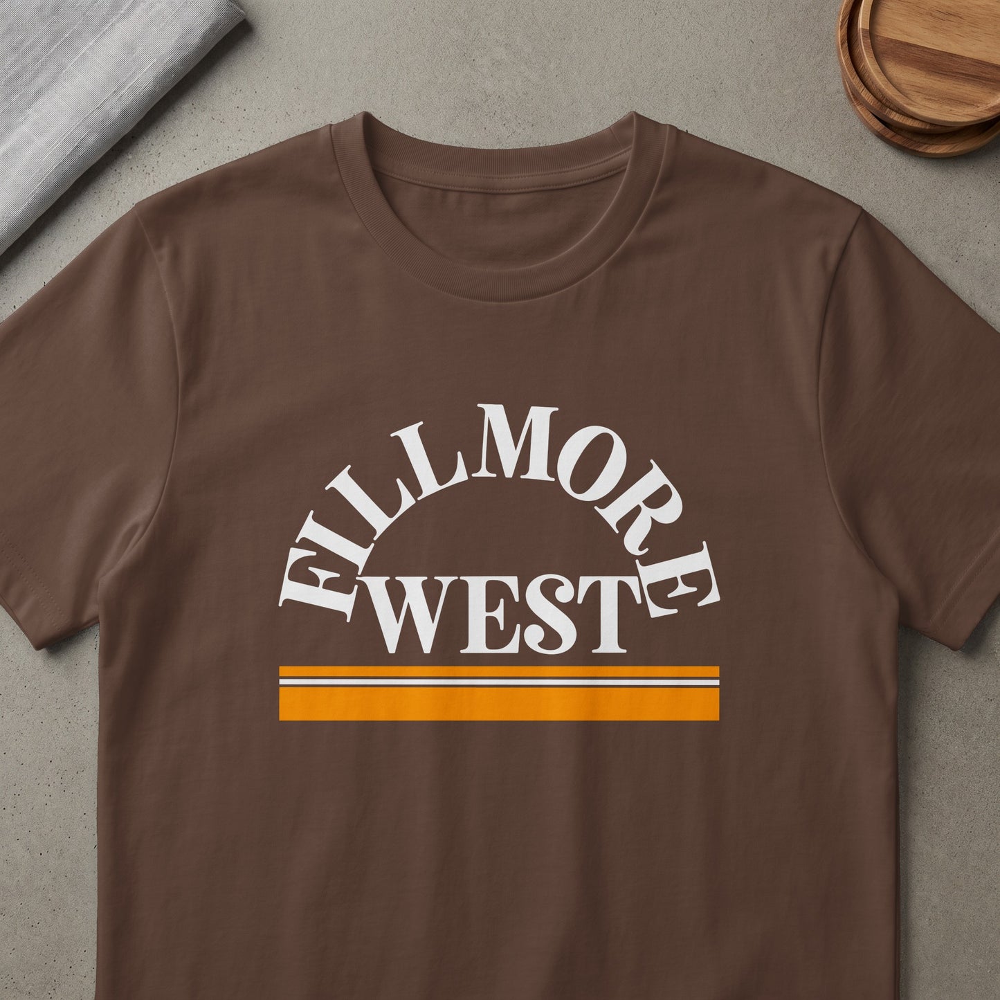 Brown t-shirt with white "FILLMORE WEST" text and orange and white stripe accent.