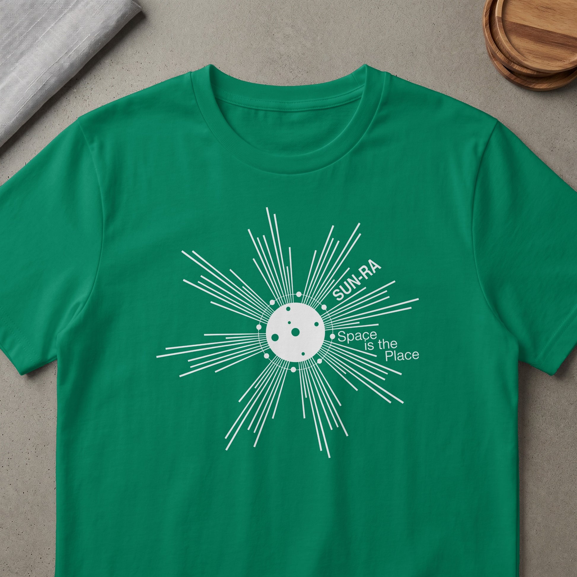Green t-shirt with white graphic of Sun Ra and text "Space is the Place".