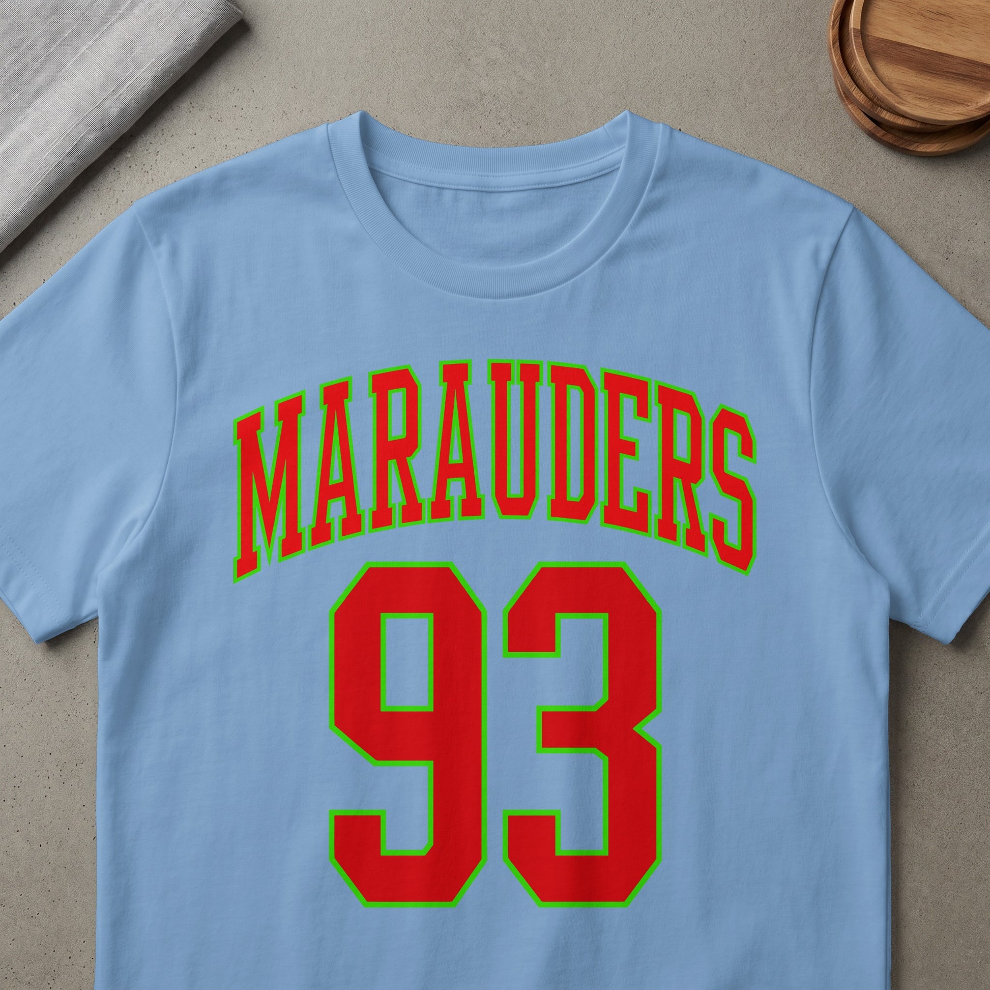 Light blue t-shirt with red "MARAUDERS 93" text outlined in green.