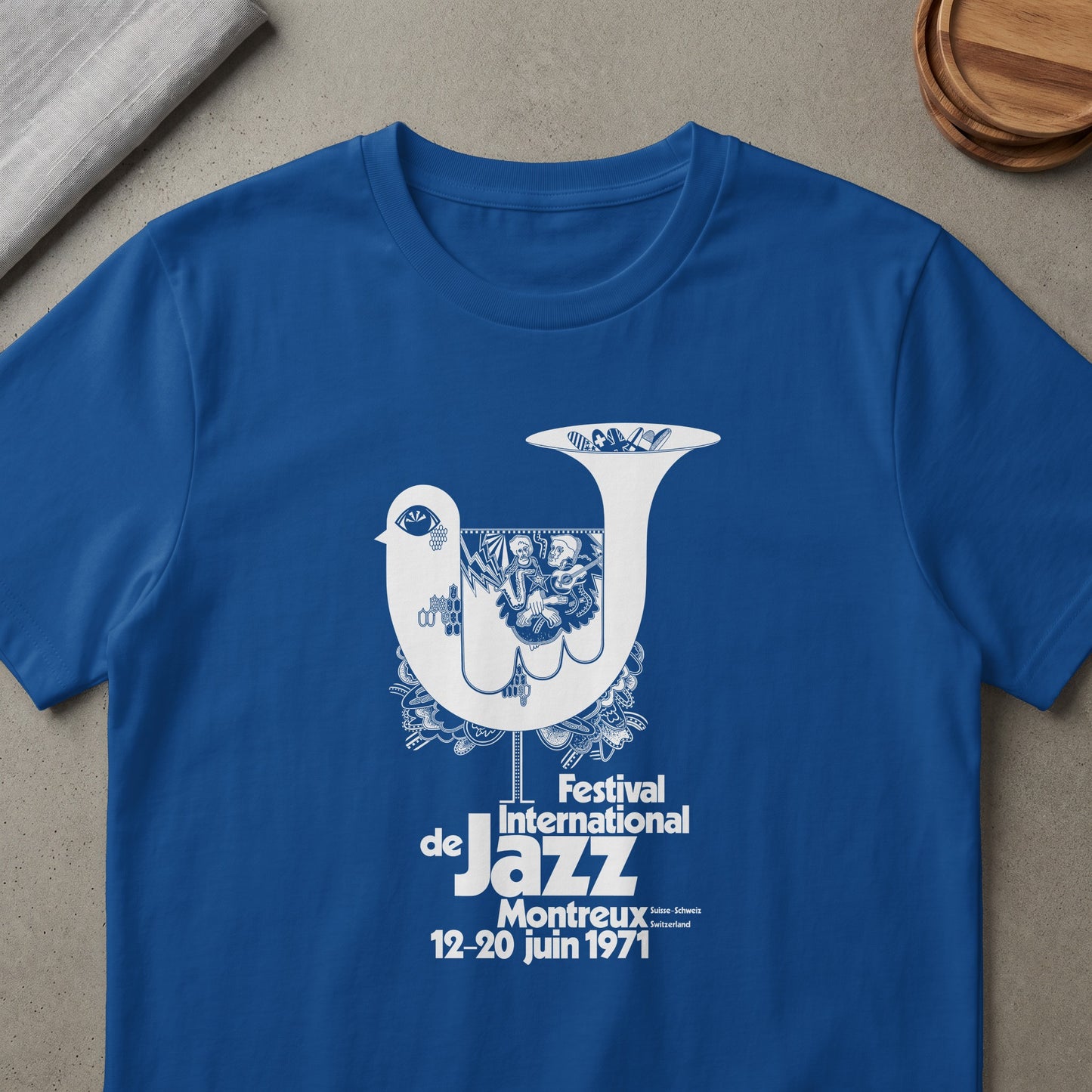 Blue t-shirt with white graphic of a stylized bird, trumpet, and text for Jazz festival.