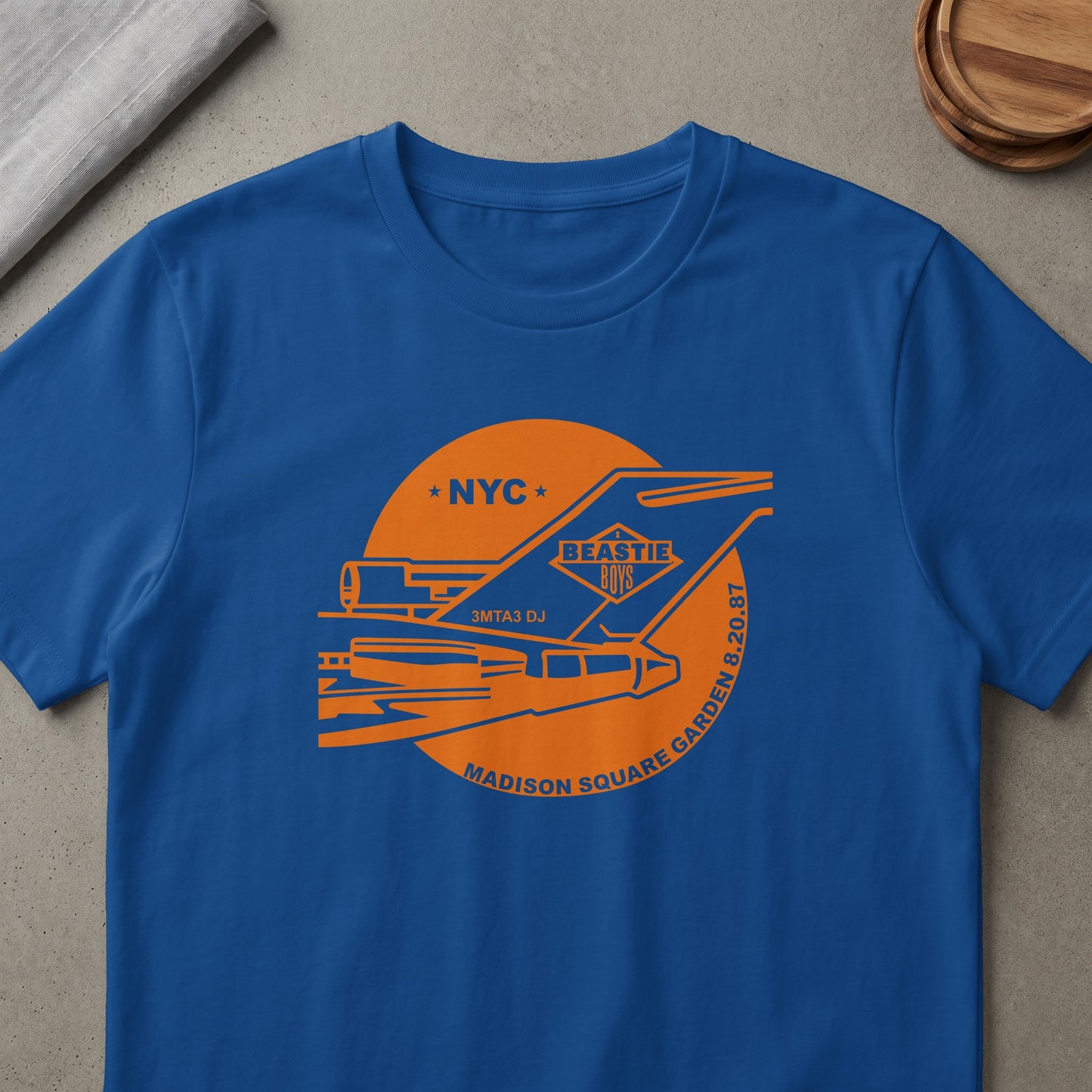 Blue t-shirt with orange Beastie Boys NYC Madison Square Garden concert graphic.