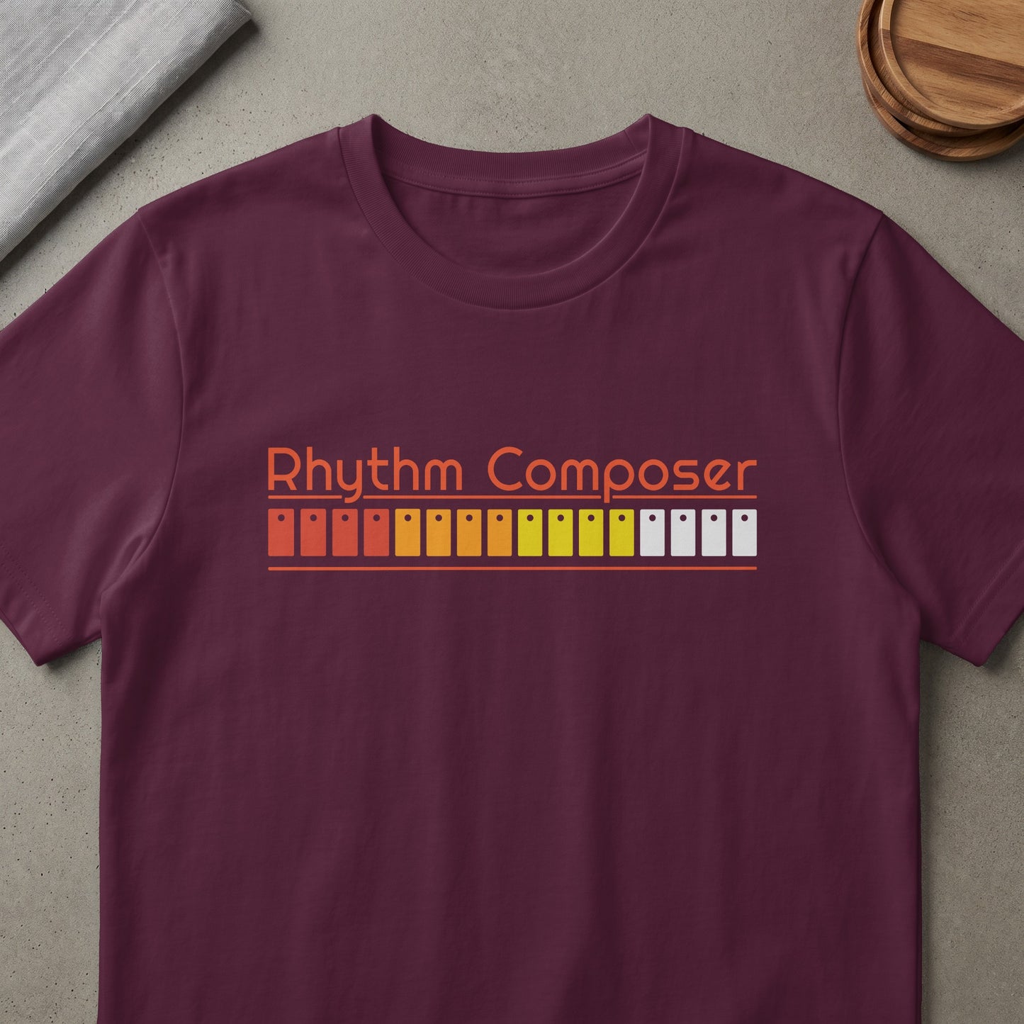 Maroon t-shirt with orange "Rhythm Composer" text and music producer buttons.
