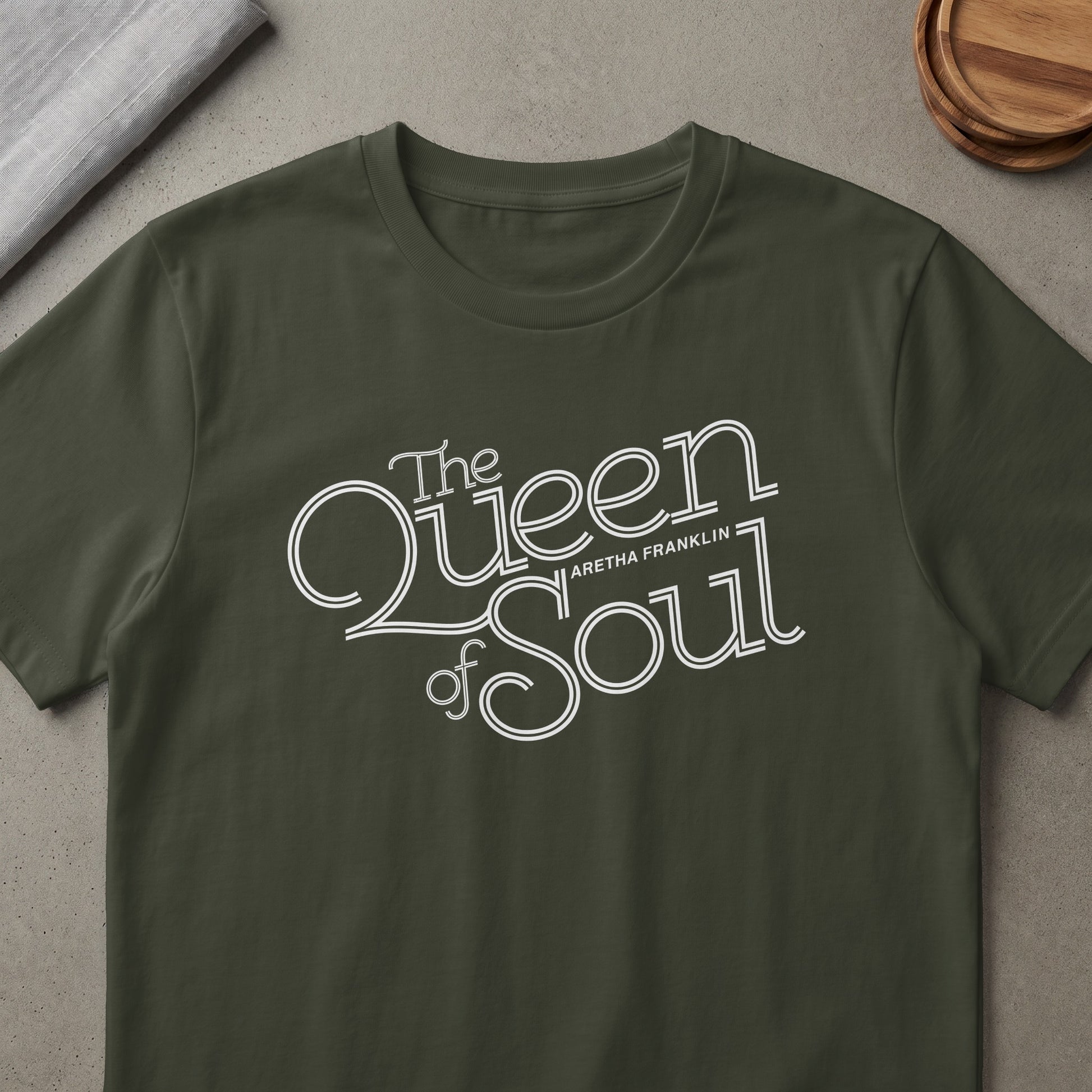 Dark green t-shirt with white text "The Queen of Soul Aretha Franklin".