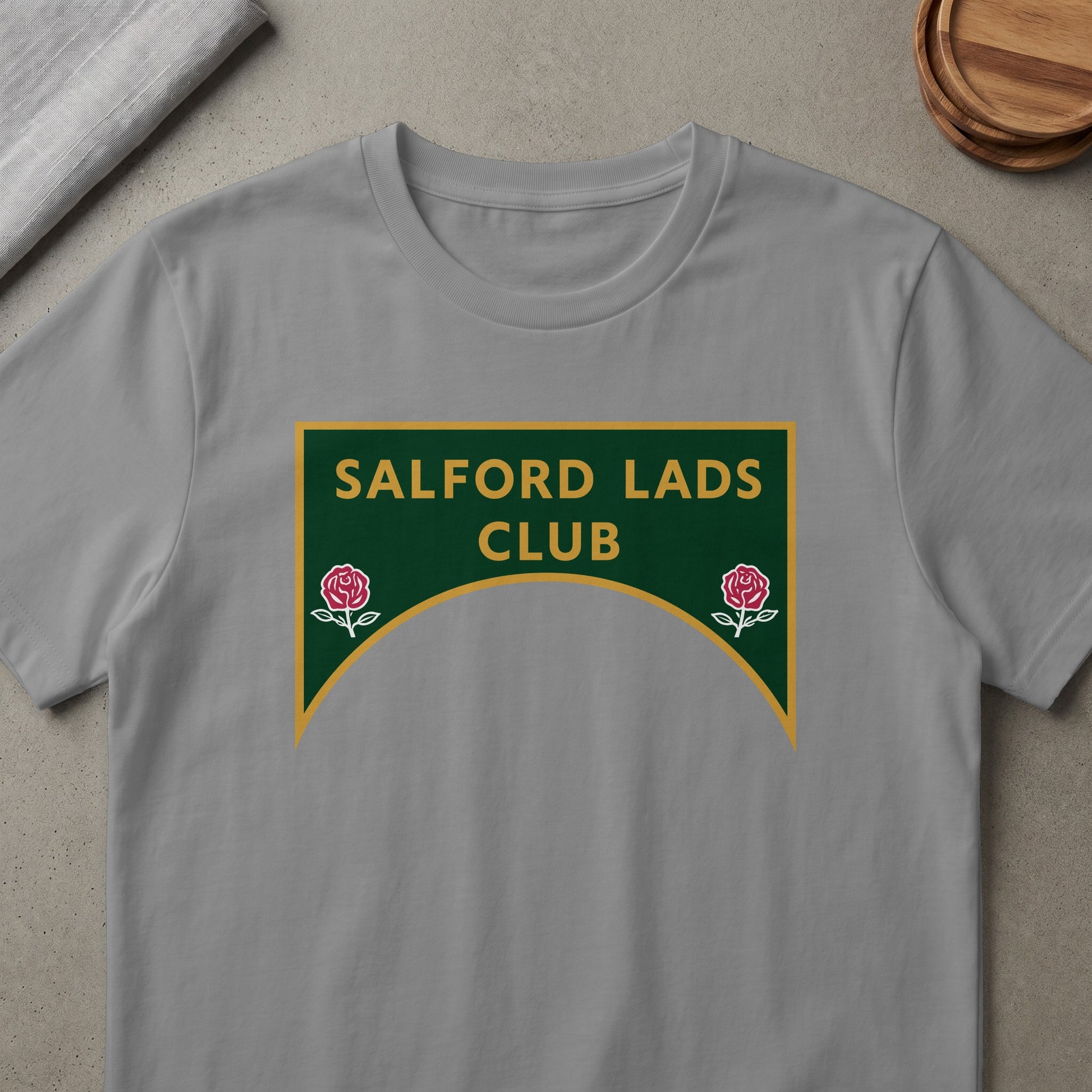 Grey t-shirt with "SALFORD LADS CLUB" and rose emblems on a green and gold sign.