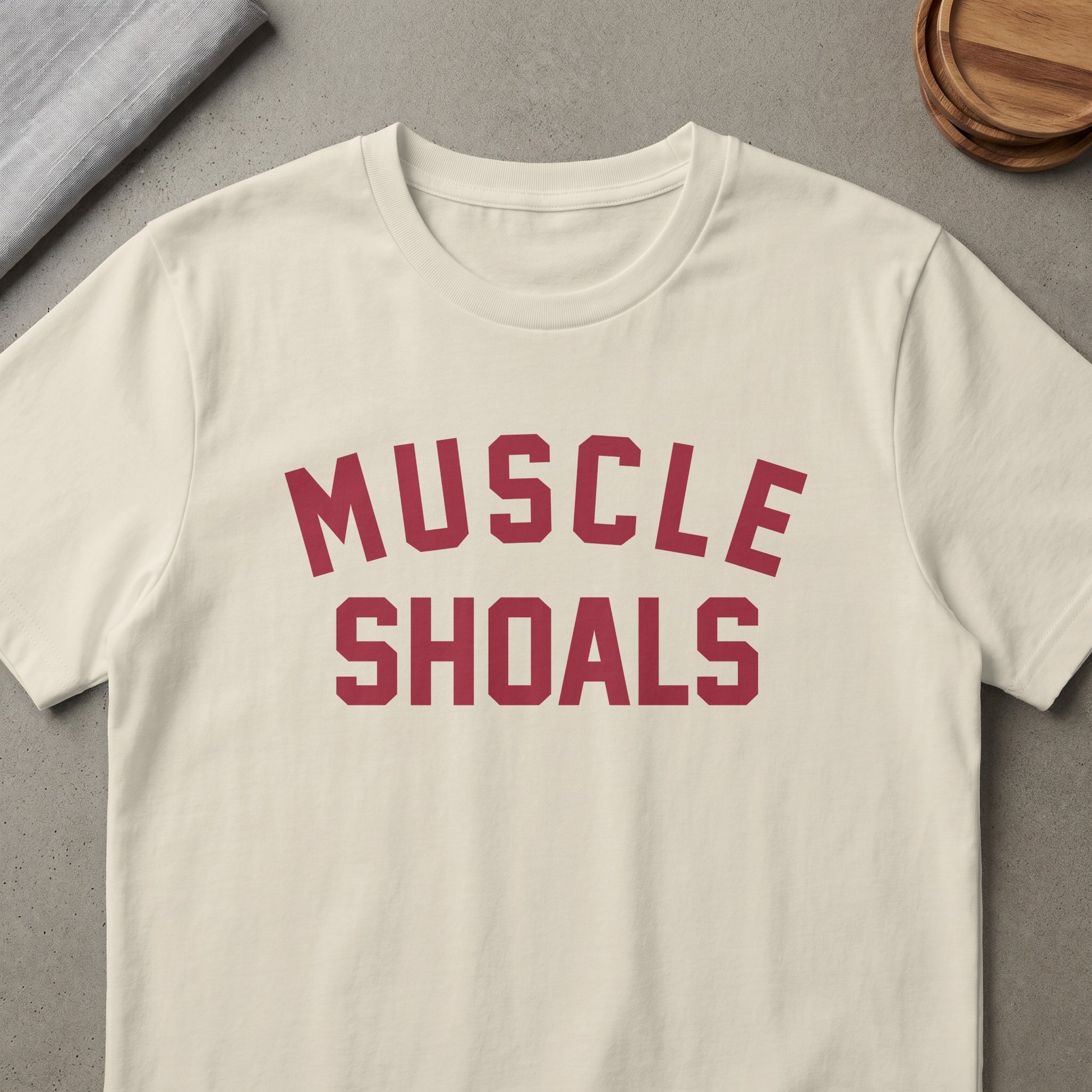 Cream t-shirt with "MUSCLE SHOALS" printed in maroon block letters.