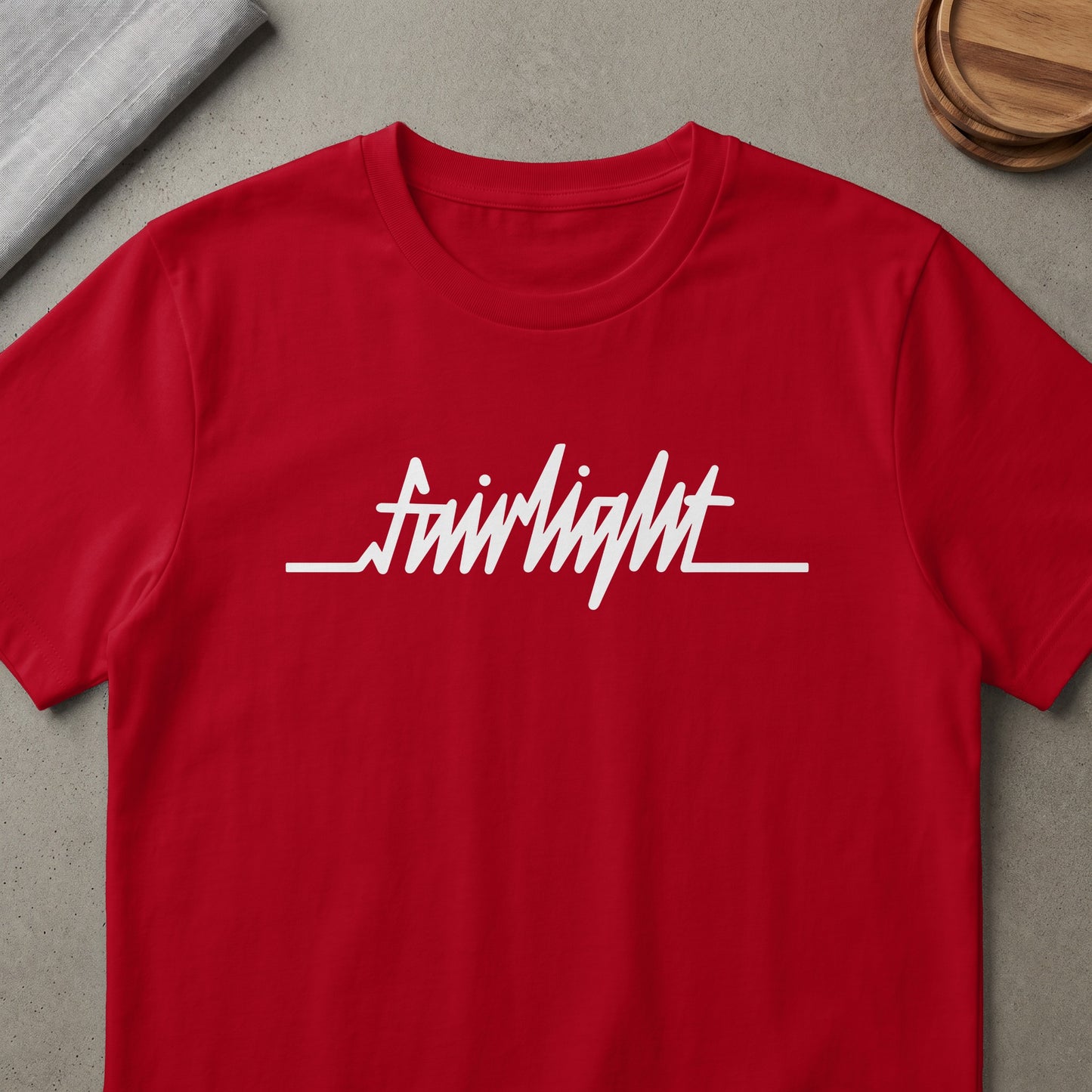 Red t-shirt with white "fairlight" script logo and waveform graphic.