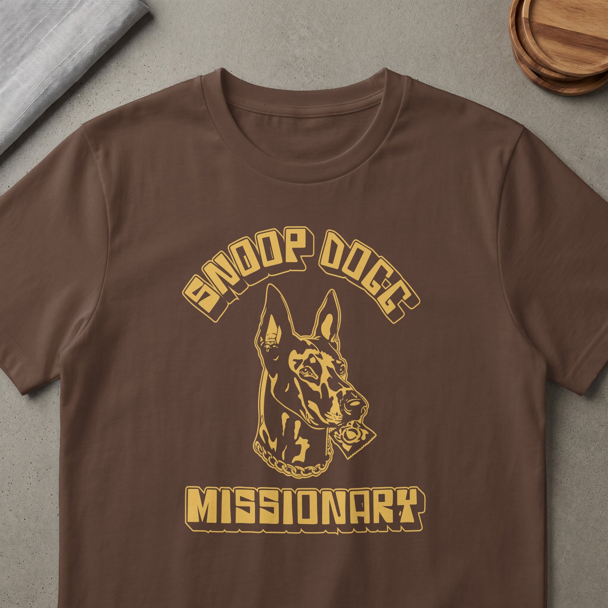 Brown t-shirt with gold Snoop Dogg Missionary graphic featuring a dog wearing a chain.