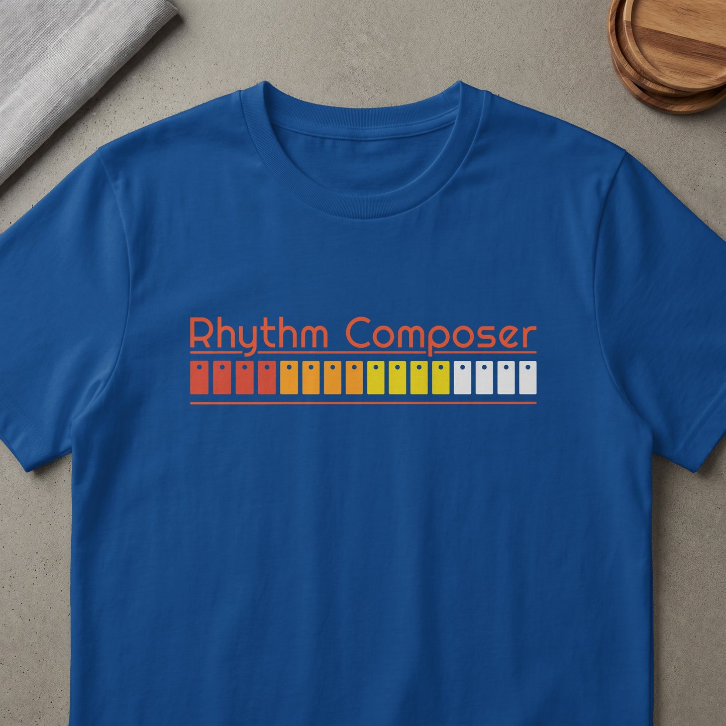 Blue t-shirt with orange text "Rhythm Composer" over colorful buttons.