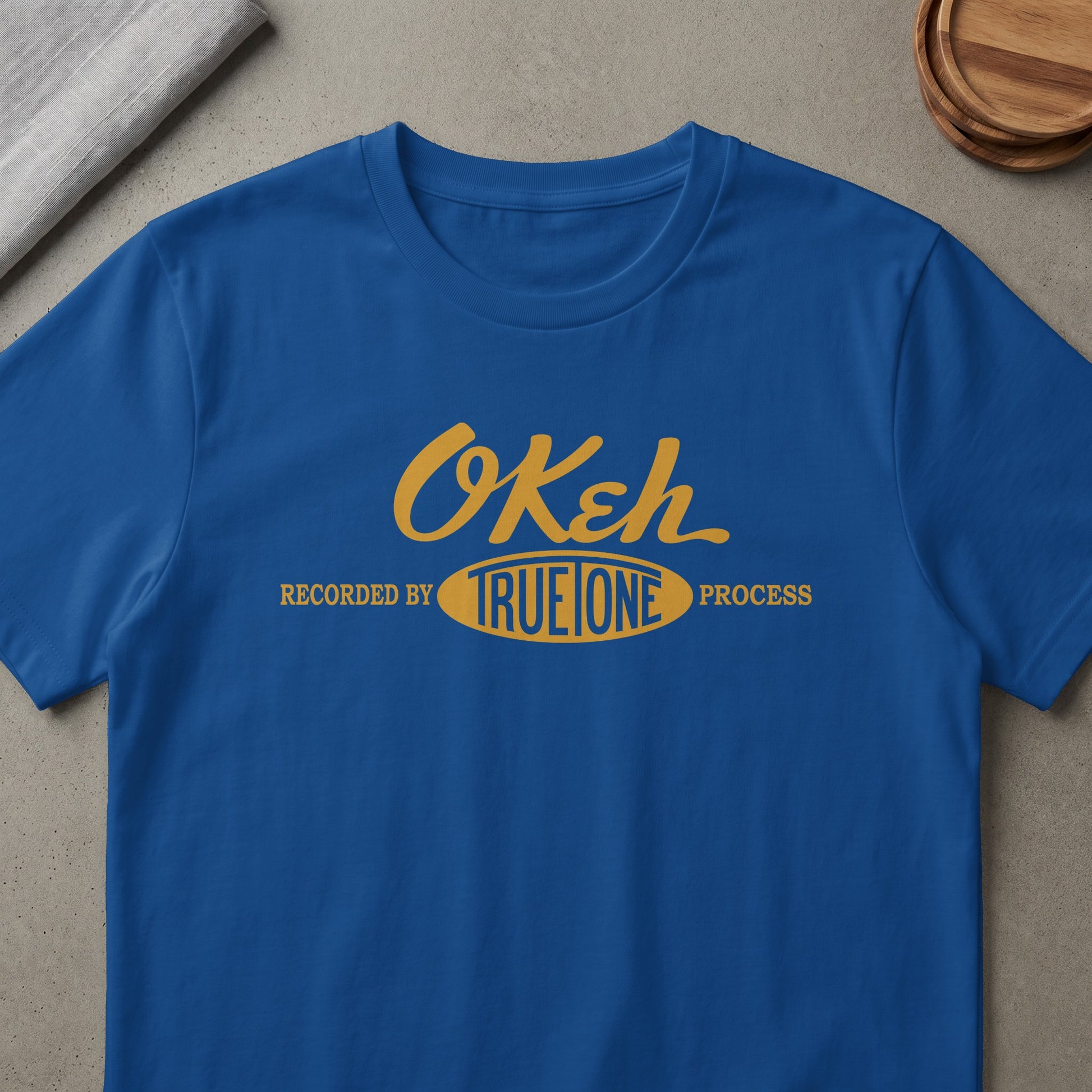 Blue t-shirt with yellow "Okeh True One Process" graphic.