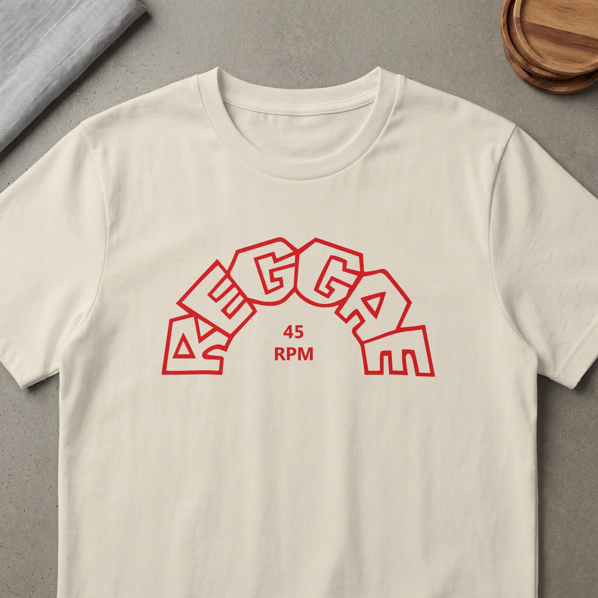 Cream t-shirt with red "Reggae 45 RPM" text in a rounded, segmented design.