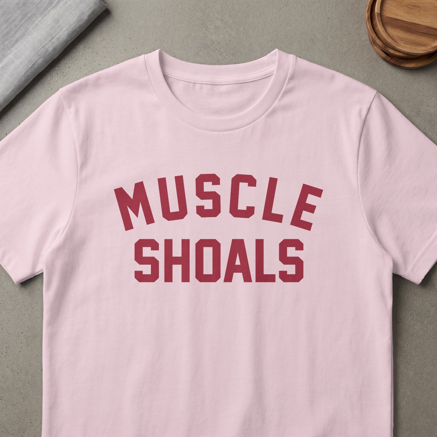 Pink t-shirt with "MUSCLE SHOALS" text in maroon athletic lettering.