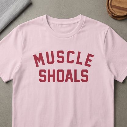 Pink t-shirt with "MUSCLE SHOALS" text in maroon athletic lettering.
