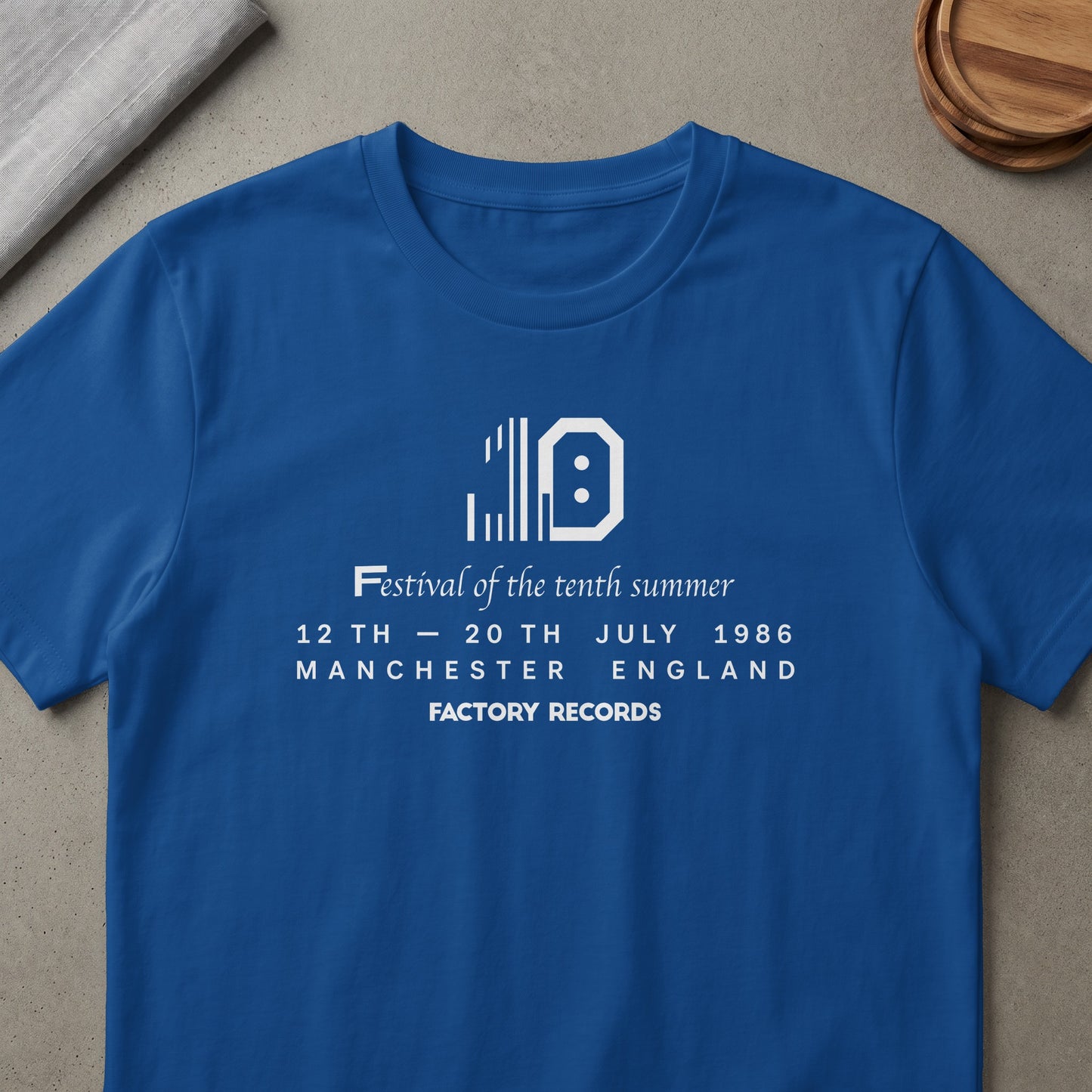Blue t-shirt with "Festival of the tenth summer 12th - 20th July 1986 Manchester England Factory Records" printed.