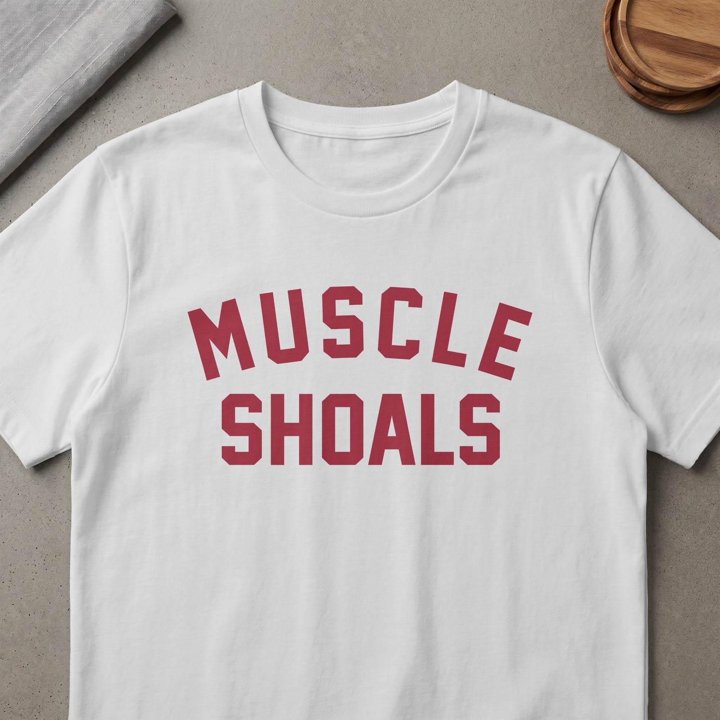 White t-shirt with "MUSCLE SHOALS" printed in red collegiate style font.